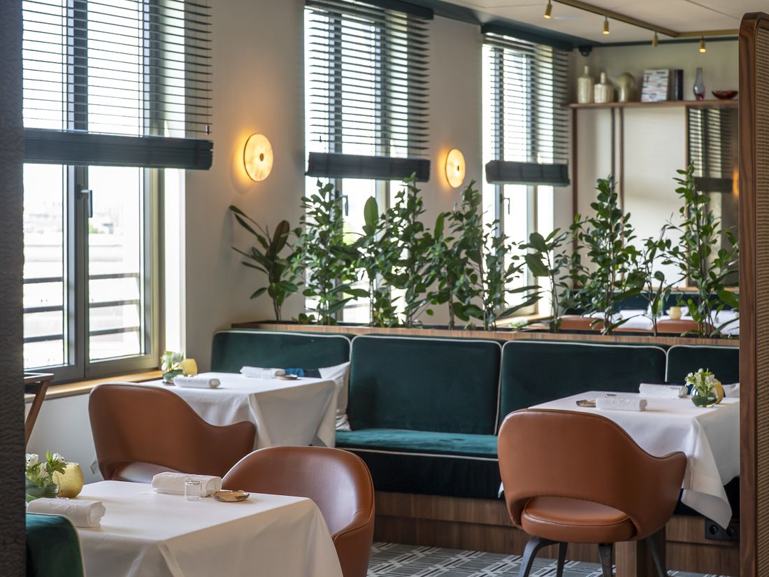 Tables and green banquettes in the dining room at Chaga